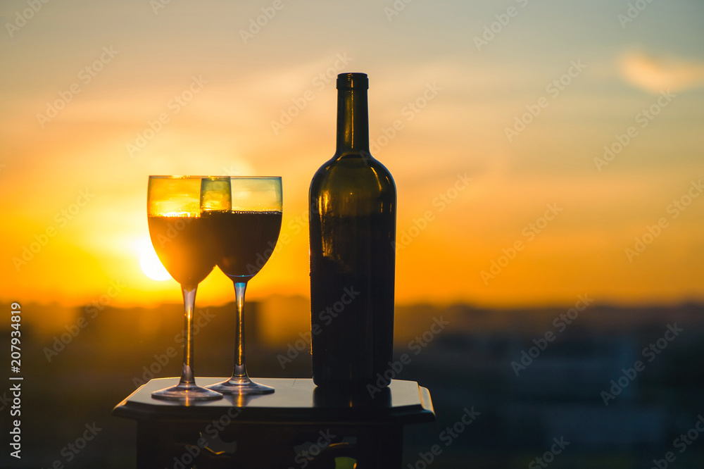 Silhouette female hand toasting wine on sunset background. Romantic couple celebrating at a restaurant