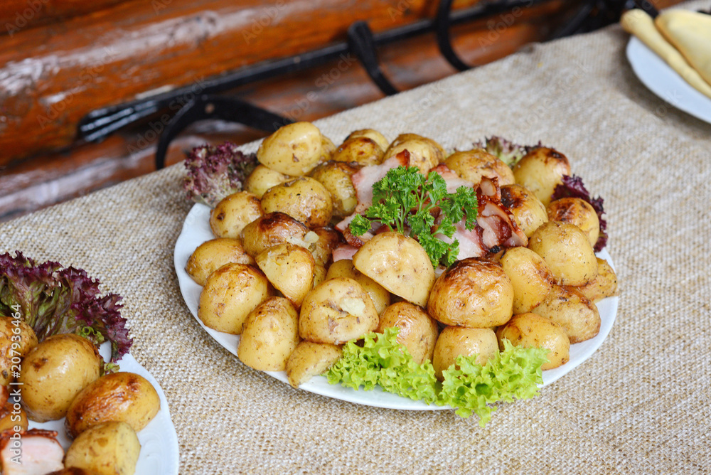 grilled potatoes with bacon served on white plate with lettuce and parsley leaves grilled potatoes with bacon served on white plate with lettuce and parsley leaves
