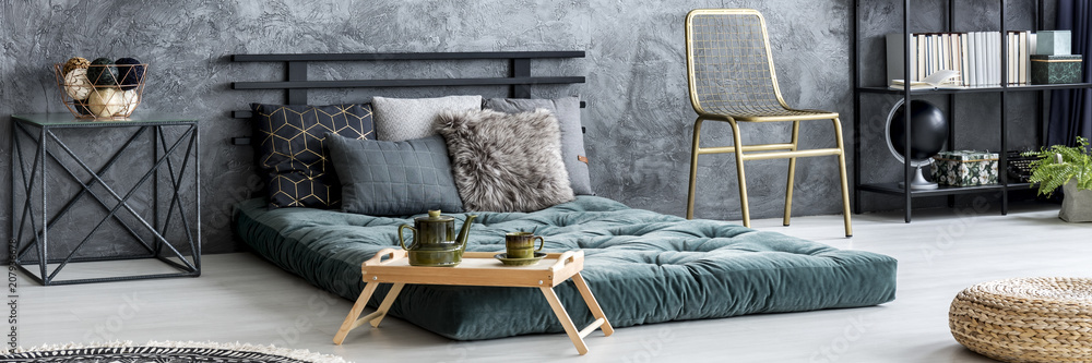 © Photographee.eu - Gold chair placed in dark bedroom interior with raw wall, green mattress bed with pillows and books on metal rack © Photographee.eu - Gold chair placed in dark bedroom interior with raw wall, green mattress bed with pillows and books on metal rack