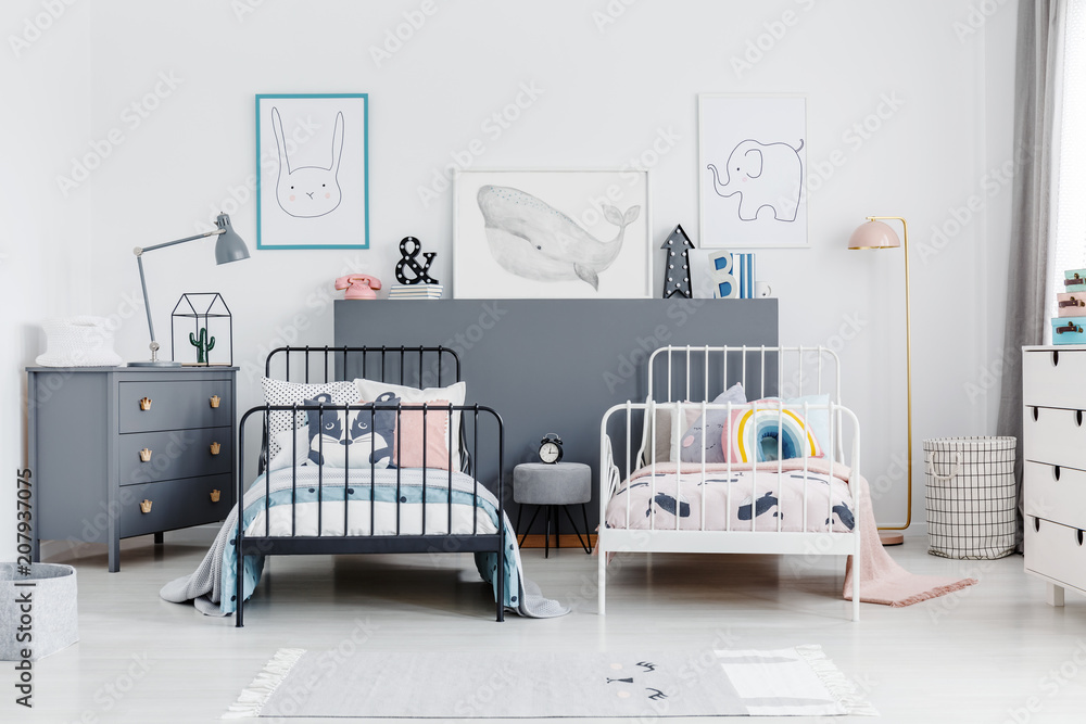 Fototapeta premium Black and white bed in siblings bedroom interior with grey cabinet and posters. Real photo