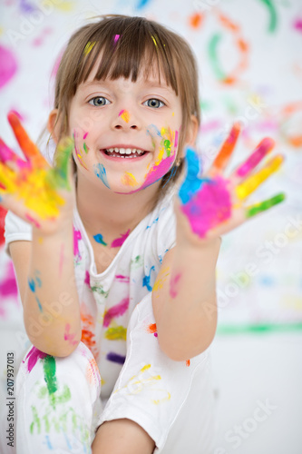 Portrait of a cute cheerful happy little girl showing her hands painted in bright colors