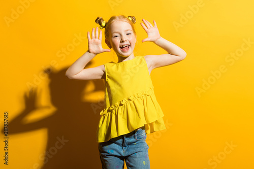 Girl with red hair on a yellow background. The girl is fooling around.
