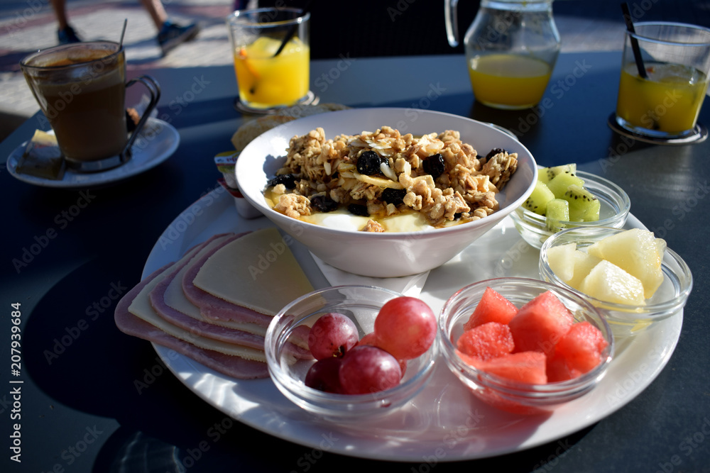 Desayuno saludable con frutas y cereales con yogur y miel en una cafetería con vista al mar
