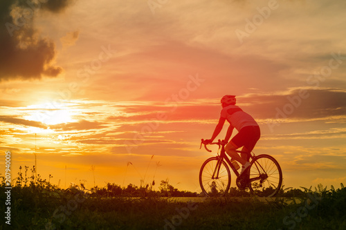 Backside of cyclist ride bicycle on sunset time in public park. Sport and active life concept.