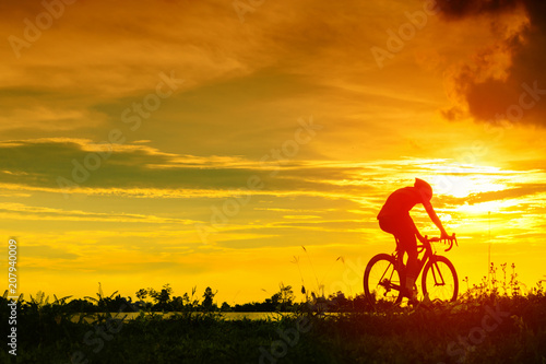 Backside of cyclist ride bicycle on sunset time in public park. Sport and active life concept. © Pattadis
