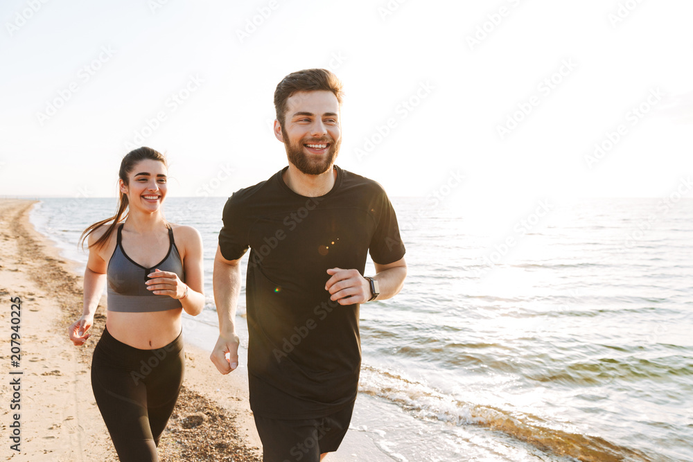 Fotografie Happy young couple jogging together on a beach