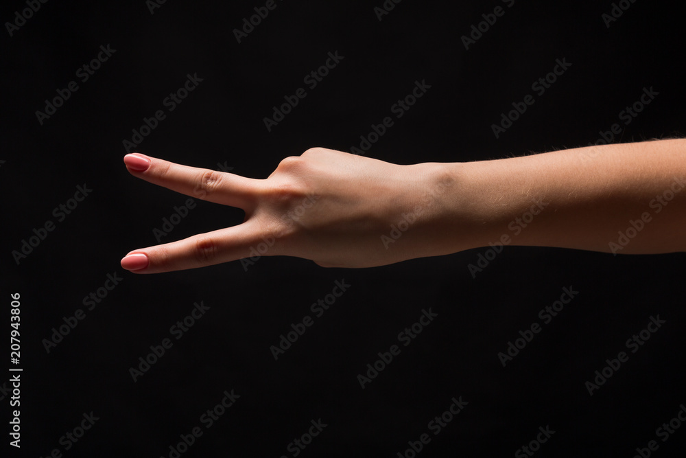 Female hand shows number two isolated at black