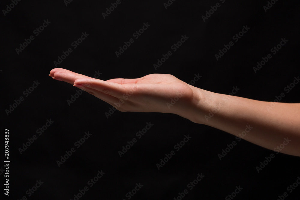 Woman holding palm open isolated on black