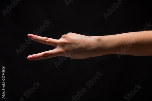 Female hand shows number two isolated at black