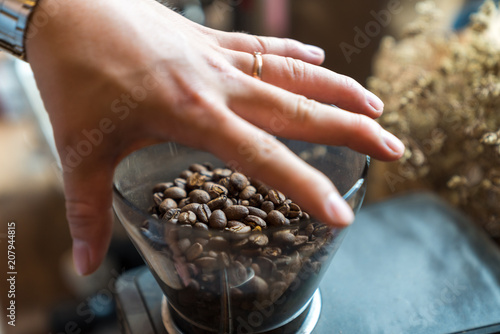 Epresso coffee bean in coffee machine jar, with barista hand