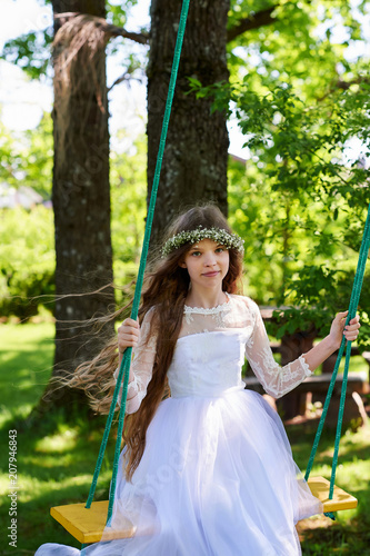 Girl in white dress swinging on the swings