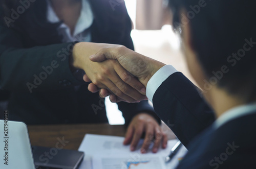 business man and business woman shaking hands for complete deal together business successful in office with stationery on table. teamwork concept. partnership concept and dealership concept.