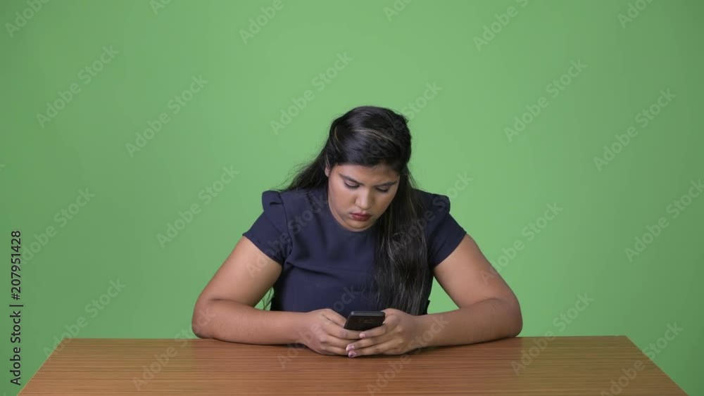 Young overweight beautiful Indian businesswoman against green background Young overweight beautiful Indian businesswoman against green background