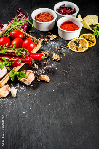 Different spices with raw and dry vegetables on black background. Top view. copy space