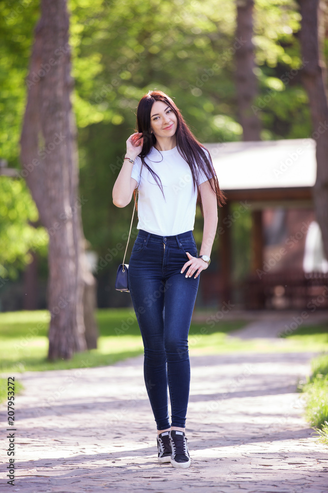 Portrait of beautiful happy stylish woman in blue jeans and white t-shirt,  walking on the street. Fashion woman lifestyle. Woman style, trendy outfit  Stock Photo | Adobe Stock