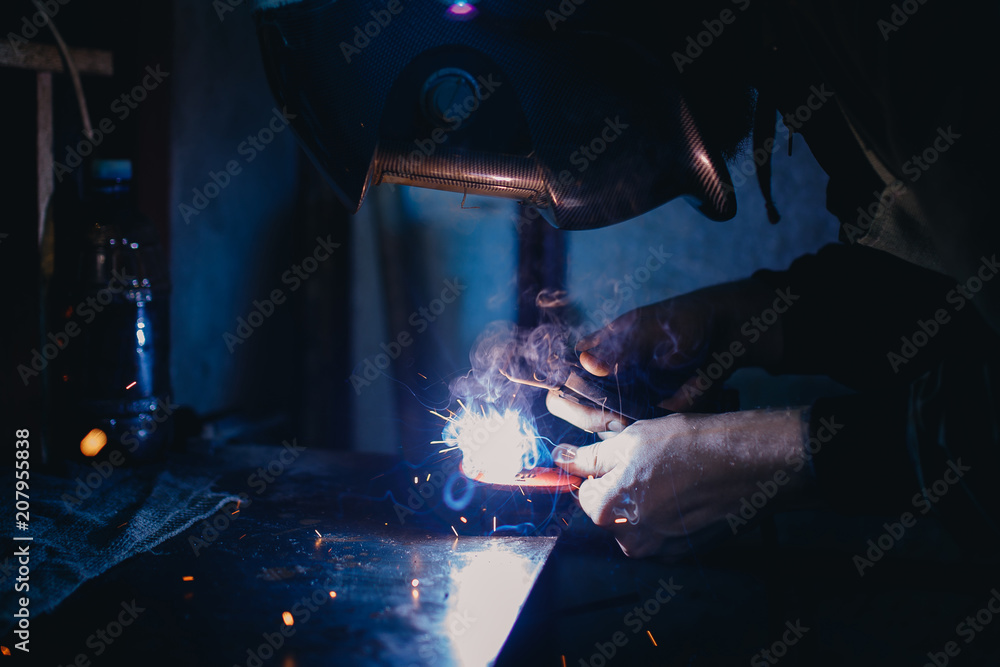 Welder man works in protective helmet, flash of light. Welder man works in protective helmet, flash of light.