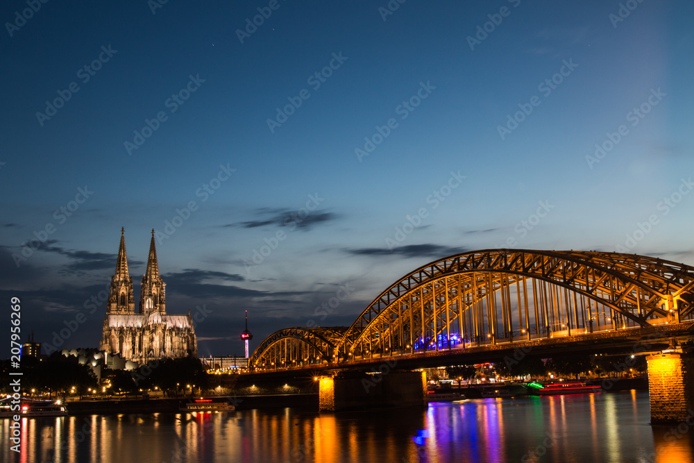 Fototapeta premium Kölner Dom beleuchtet mit Hohenzollernbrücke