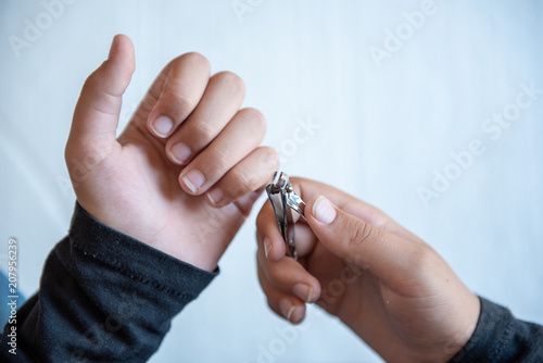 Hands of the child with nail clipper  clipping the nails on his own