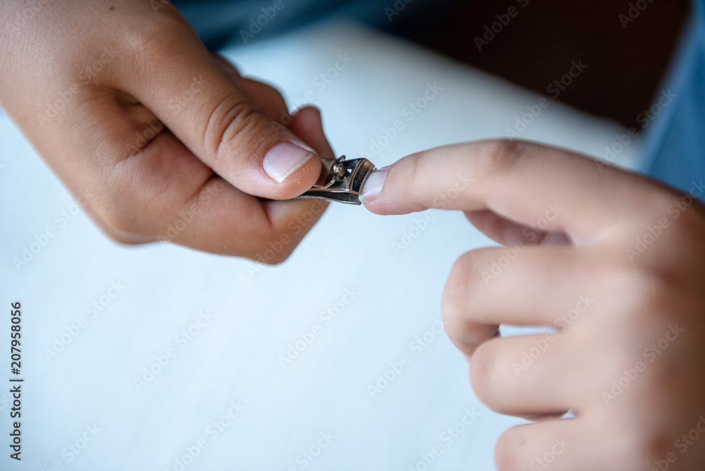 Hands of the child with nail clipper, clipping the nails on his own