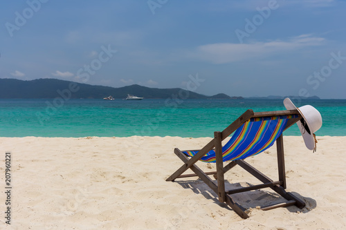 The white hat lies on the edge of the chaise longue  the seashore with a beautiful view.