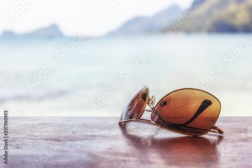 Beach vacation. Sunglasses on a wooden table on a background, beach, ocean, hot summer day. Time for rest, happy way of life.