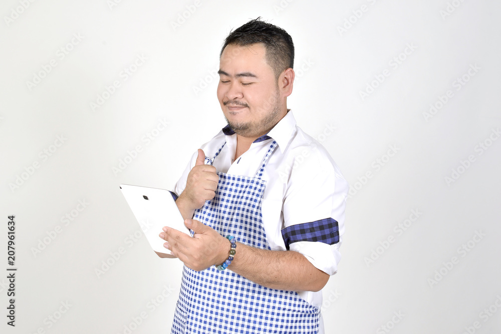 merchant Asian man in white and blue apron is feeling surprised or excited when get good news from connection internet in tablet with white background
