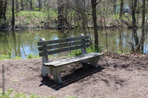 The empty wooden bench near the water of the creek.