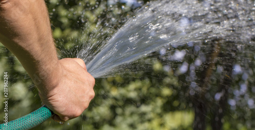 Man watering garden with hose, close-up photo