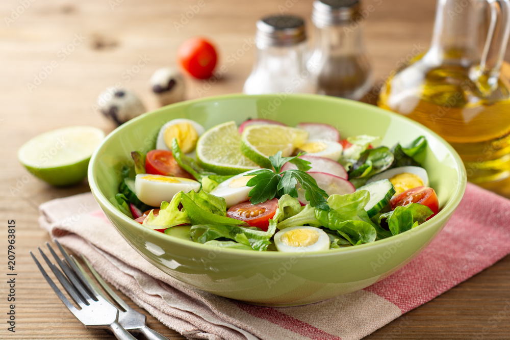Fresh salad with vegetables and quail eggs on rustic wooden background Fresh salad with vegetables and quail eggs on rustic wooden background
