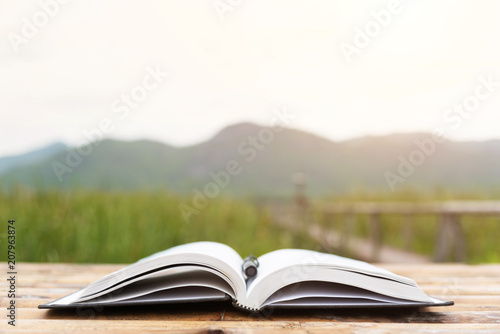 Book and pen with field and mountain background.