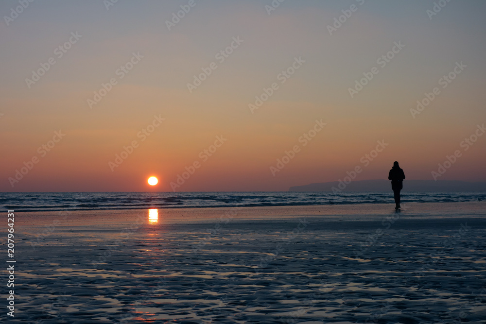 Person in silhouette on a beach at sunset