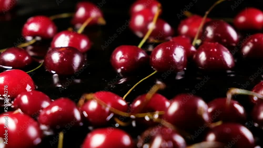 Cherries berries fall on the water on a black background, slow motion Cherries berries fall on the water on a black background, slow motion
