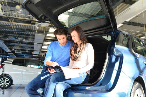 young couple in a car dealership - advice and purchase of a new car in the showroom 