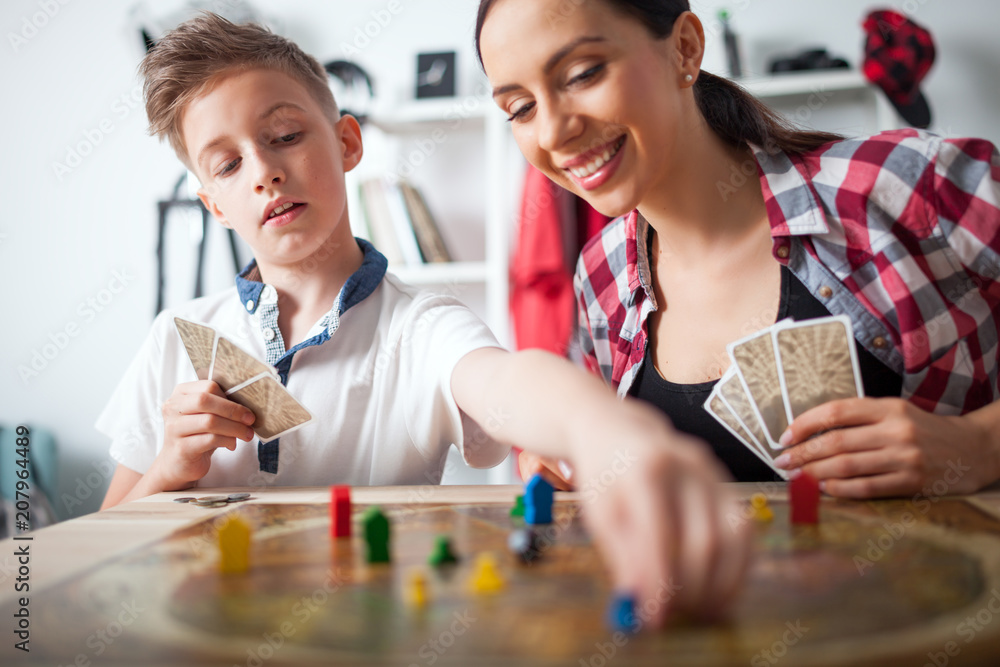 Mother and son playing modern board game in teenage room at home