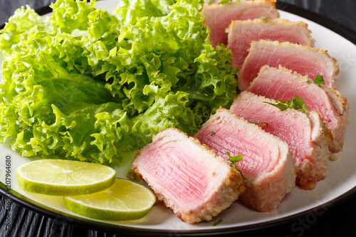 seared ahi tuna in breading with lettuce and lime closeup on a plate. horizontal