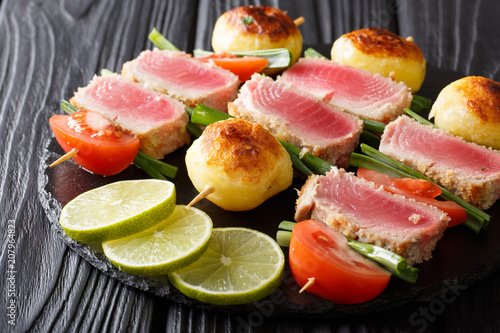Barbecue of fresh tuna, tomatoes, potatoes and green onion on skewers close-up on the table. horizontal