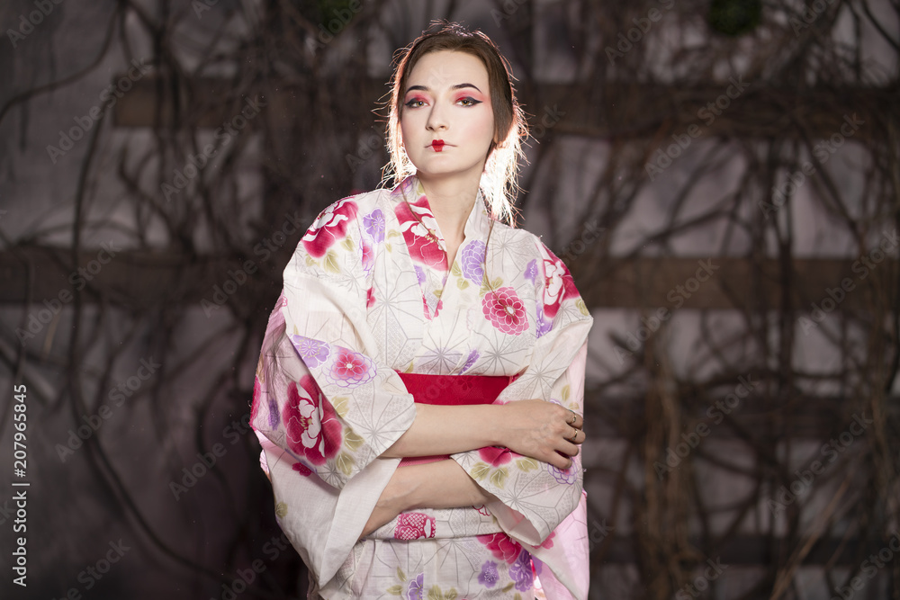 elegant girl in a classic traditional dress Japanese kimono white and pink standing alone on dark background in the studio elegant girl in a classic traditional dress Japanese kimono white and pink standing alone on dark background in the studio