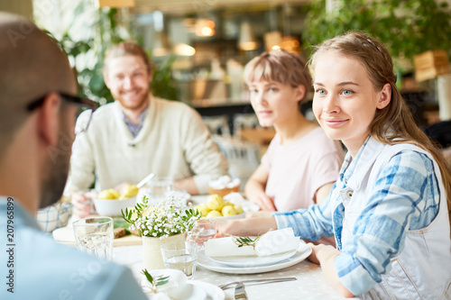 Crop view of smiling young pretty woman spending time with friends in restaurant