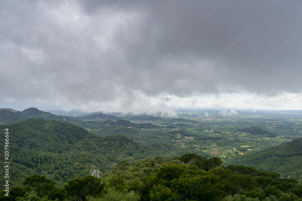 Mallorca, Rainy dark clouds over green mountainous nature landscape from above