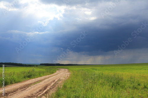 Landscape of a summer road in the field. Approach of the rain. photo