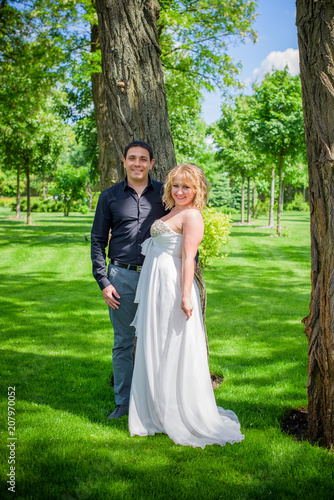 Bridal wedding plus size couple woman and man sitting with heads together on park.    