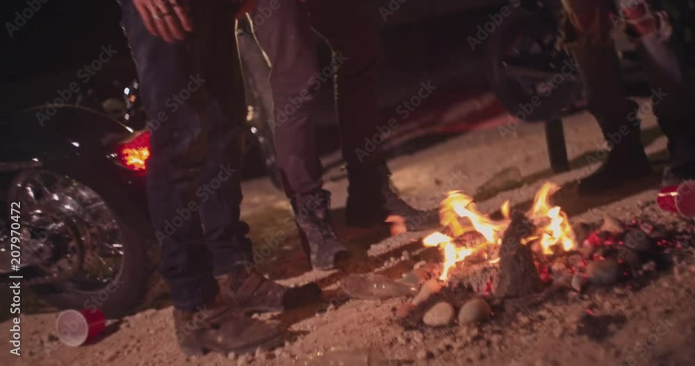 Close-up of motorcyclists' legs around campfire during party Close-up of motorcyclists' legs around campfire during party