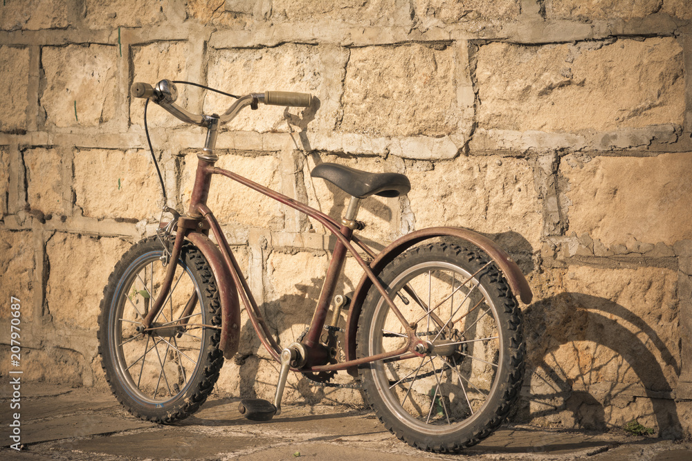 Old rusty bicycle near a brick wall