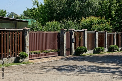 part of a brown private fence with closed gates in the street near the road