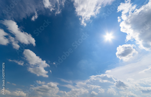 Blue sky with fluffy clouds and sun
