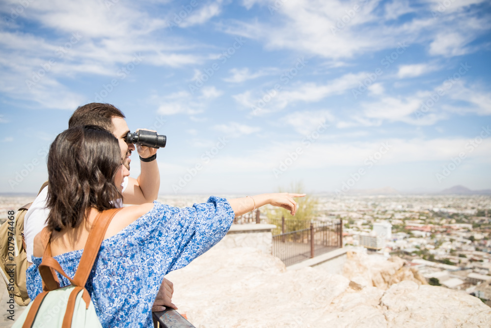 Happy young couple looking with binoculars Happy young couple looking with binoculars