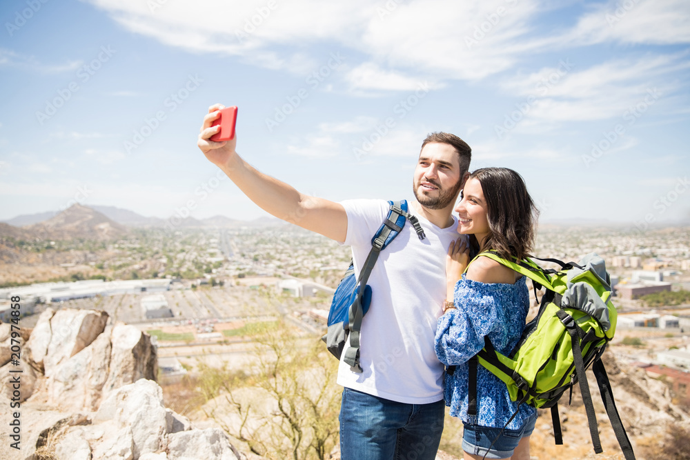 Young couple of travelers is doing selfie on a hill Young couple of travelers is doing selfie on a hill