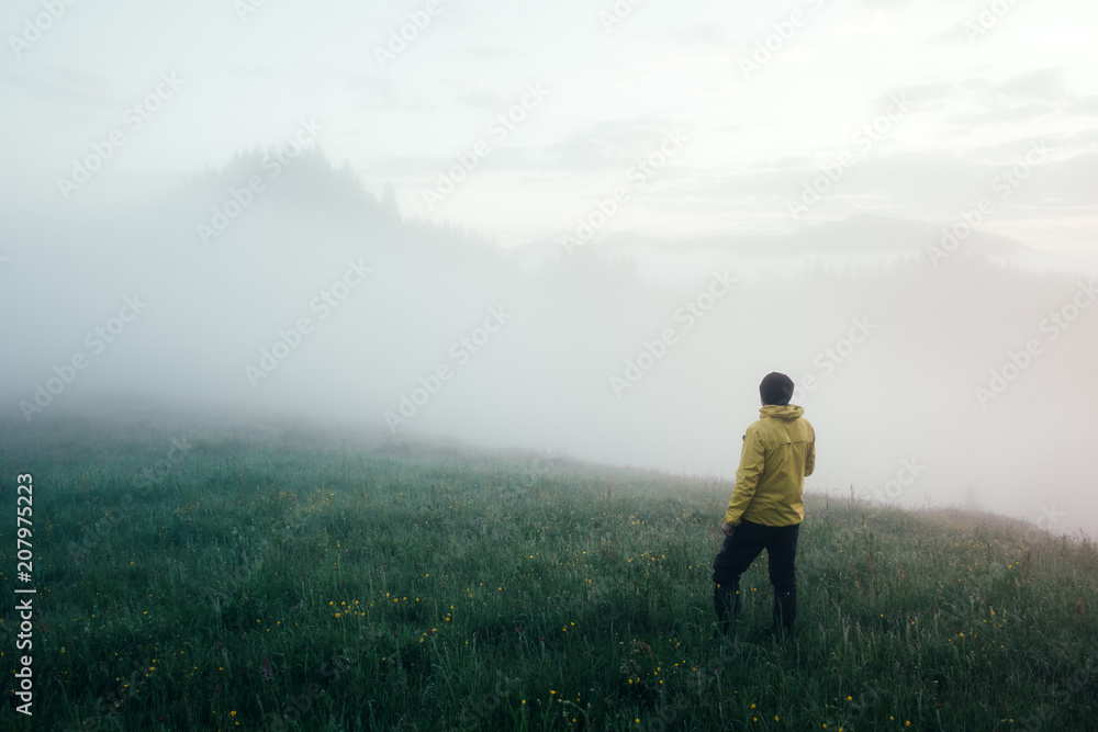 Alone tourist in yellow jacket meets the dawn on high mountains.