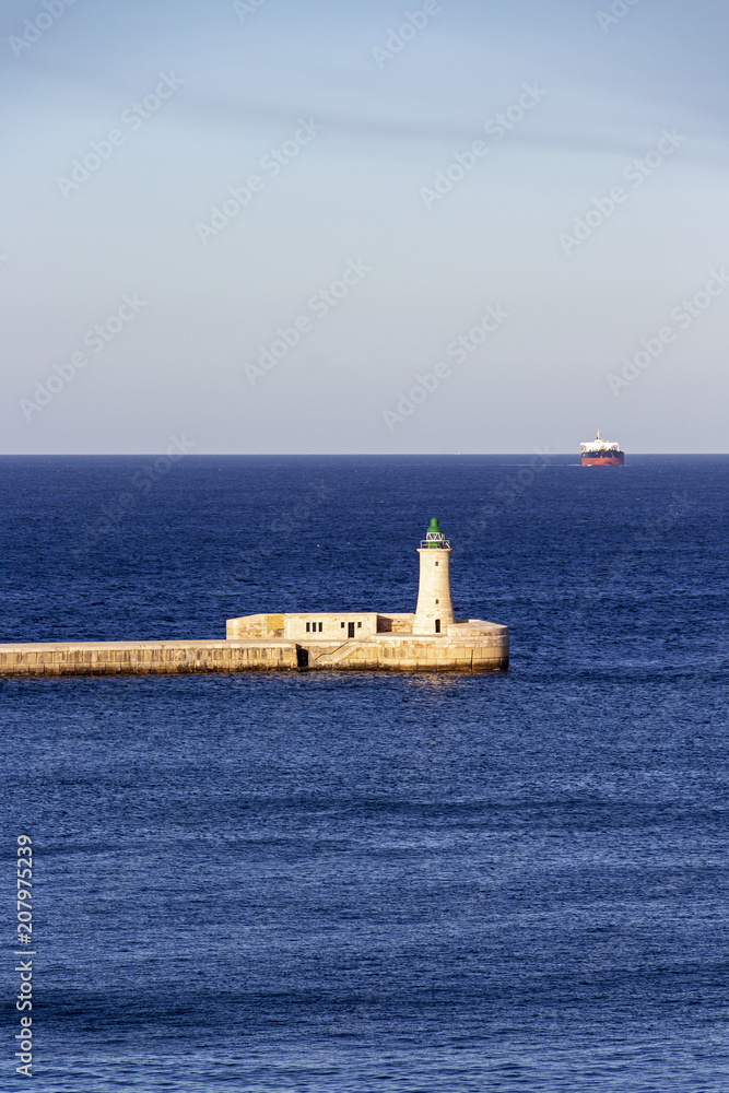 Seascape with St. Elmo Breakwater Lighthouse and a ship in the distance, at Grand Harbor, Malta
