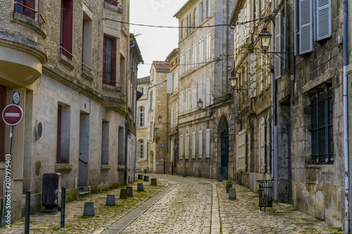 View of a cobblestone street with old buildings in Angouleme, France. The buildings look worn but dreamy and beautiful.